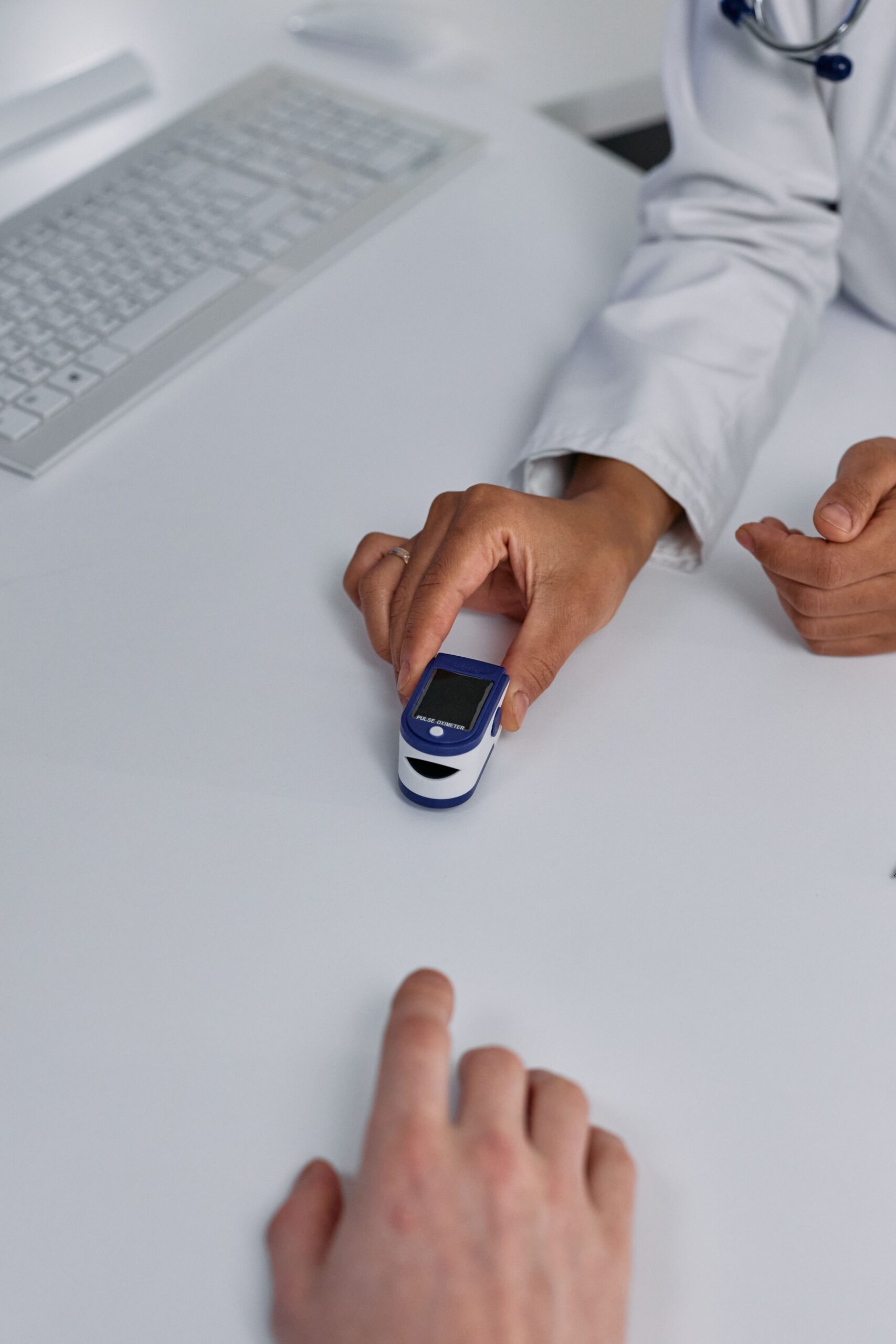 A doctor checks a patient's oxygen levels with a pulse oximeter during a consultation.